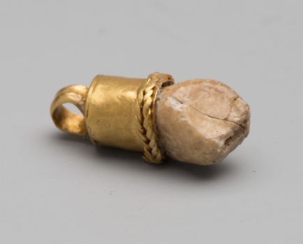 Амулет в виде зуба ребёнка в золотой оправе.